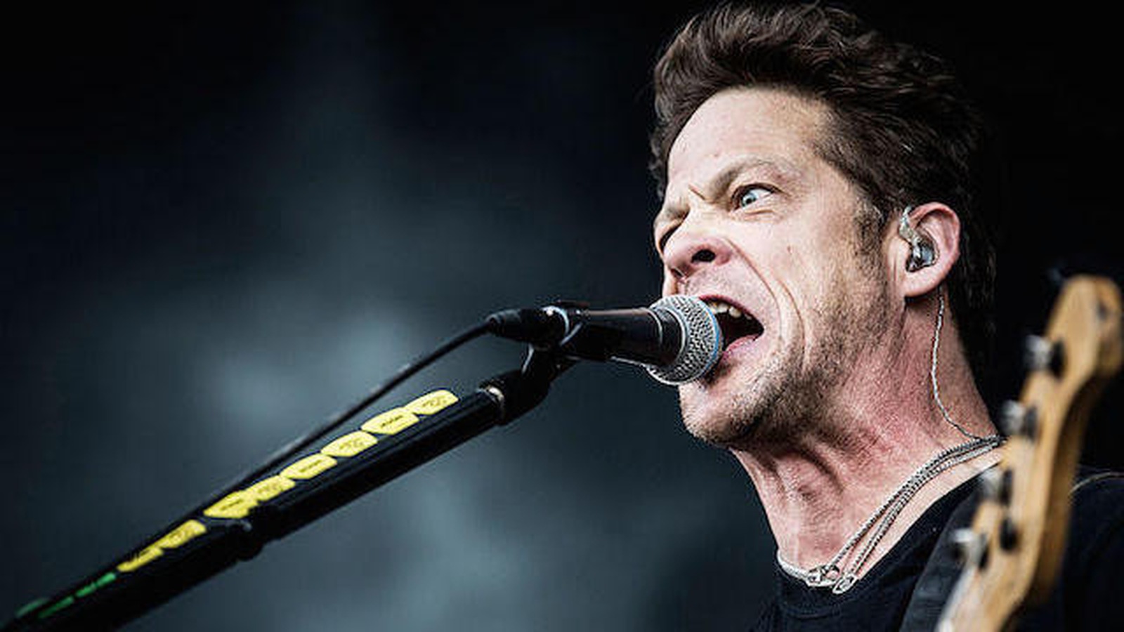 Jason Newsted performing live with a bass and singing into a microphone
