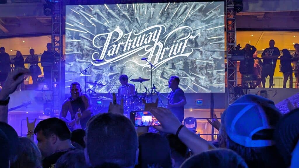 Parkway Drive performing live on the ShipRocked 2025 main deck stage at night with crowd raised hands and stage lighting