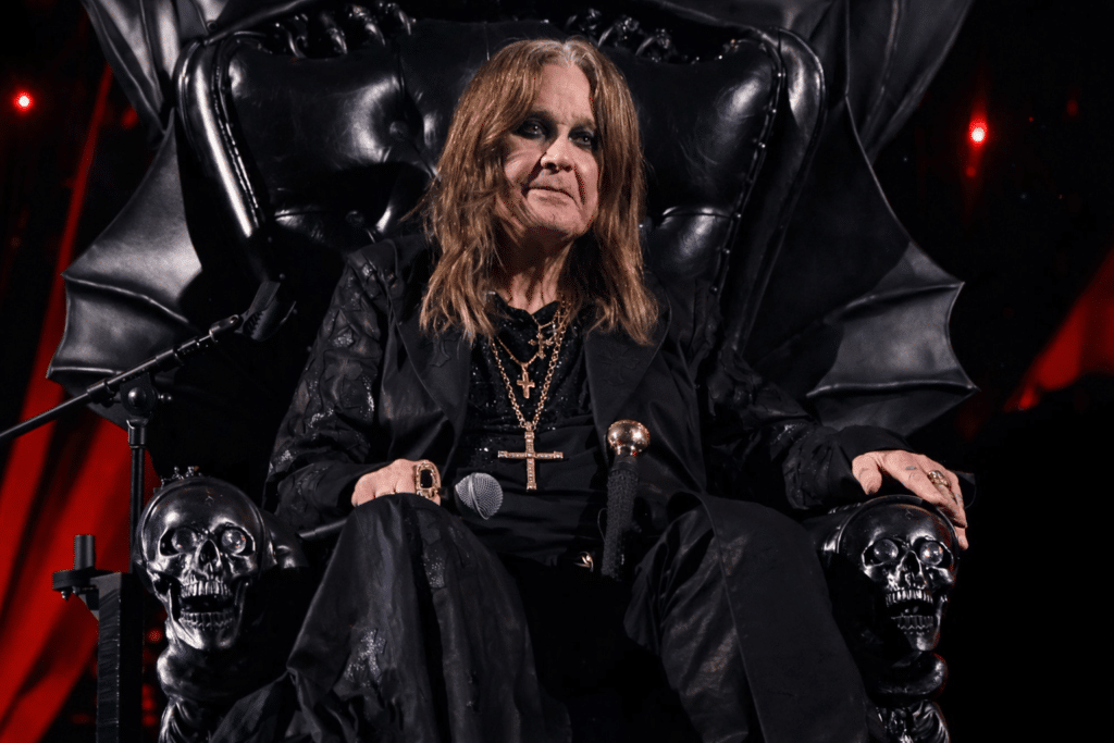 Ozzy Osbourne seated on his black throne during his final live performance, wearing black with cross necklaces, the Prince of Darkness bidding farewell to fans
