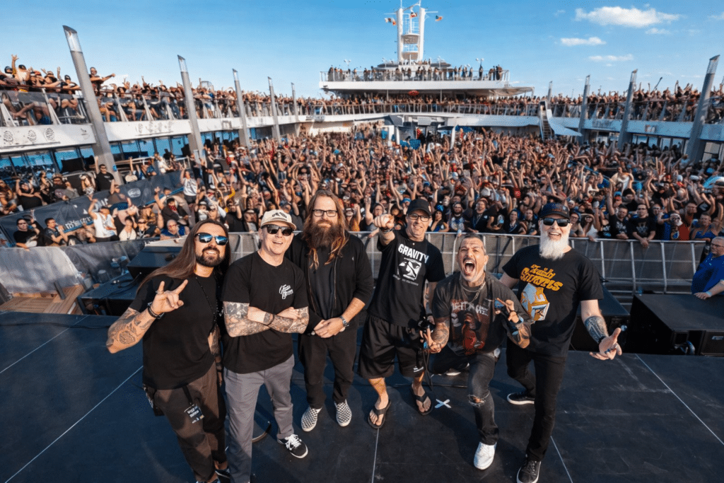 Lamb of God posing on stage aboard Headbangers Boat with a massive crowd of metal fans on a cruise ship deck